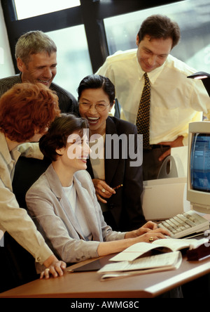 Five businesspeople gathered around desk, smiling Stock Photo
