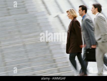 Three business people walking side by side, side view, blurred Stock Photo