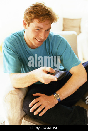 Man sitting, holding remote control, close-up Stock Photo