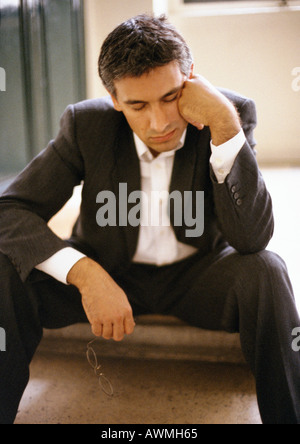 Man sitting on steps, leaning head against hand, eyes closed, mid-length, close-up Stock Photo