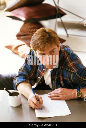 Man sitting at table, writing, high angle view Stock Photo