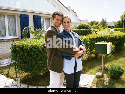 Couple standing in front of house, embracing Stock Photo