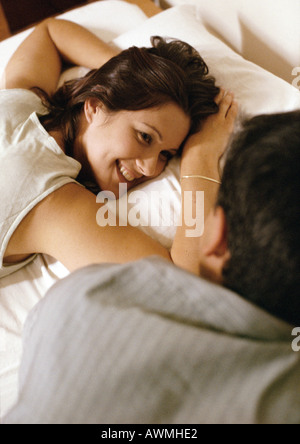 Woman lying on bed, looking at man in foreground Stock Photo