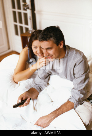Couple sitting on bed, man holding remote control Stock Photo