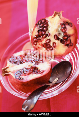 Pomegranate cut in half, in bowl with spoon, close-up Stock Photo