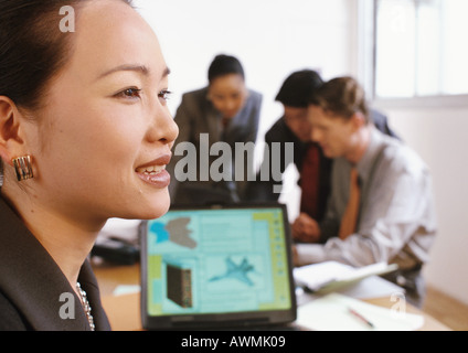 Businesswoman smiling, three people interacting in background Stock Photo