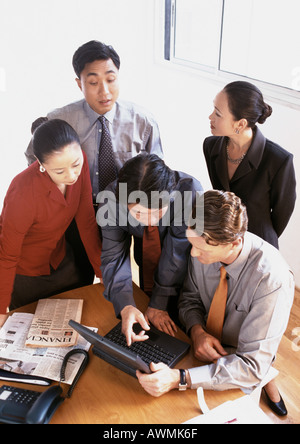 Five business associates gathered around laptop computer on table, high angle view Stock Photo