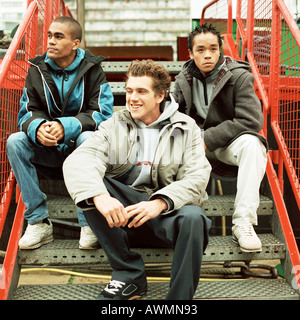 Three young men sitting on stairs Stock Photo