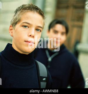 Teenage boy looking into camera, second teenager in background Stock Photo