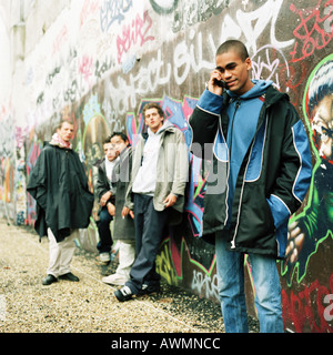 Five young men in front of wall covered in graffiti Stock Photo