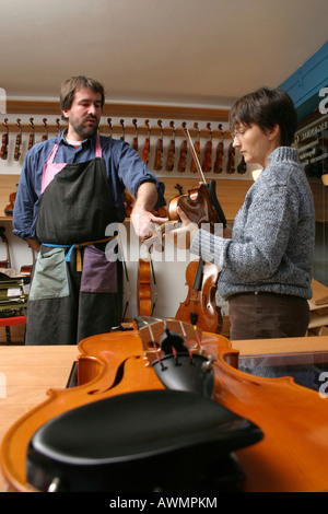 Violin-maker (luthier) with a customer in his shop Stock Photo