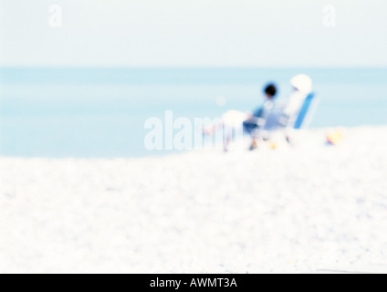 People sitting on chairs on the beach, blurred Stock Photo