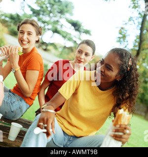 Young women eating sandwiches together outside Stock Photo