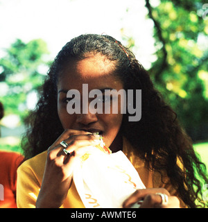 Young woman eating sandwich outside, portrait. Stock Photo