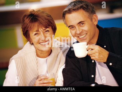 Man and woman sitting together smiling, man holding mug, close up Stock Photo