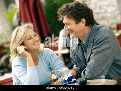 Man and woman sitting at table, smiling at each other Stock Photo
