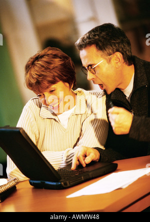 Man and woman sitting at table looking at laptop computer together Stock Photo