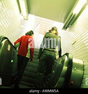 Young women going up escalator, rear view Stock Photo