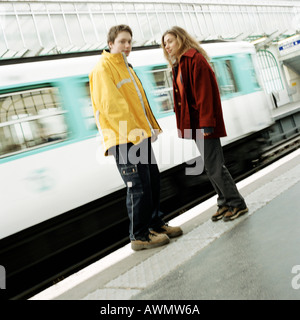 Young people standing on platform, in front of moving subway train, blurred Stock Photo