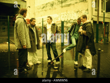 Young men hanging out together on street corner, wall with grafitti in background Stock Photo