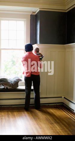 Mother holding baby next to window