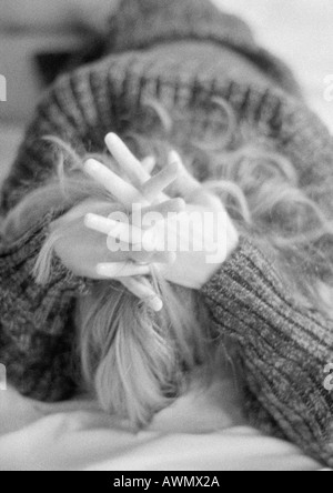 Woman lying on bed face down, hands clasped behind head, black and white Stock Photo