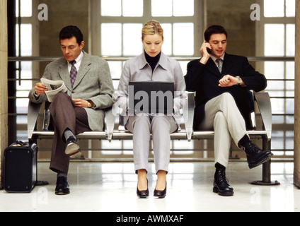 Businesswoman using laptop sitting between two businessmen. Stock Photo