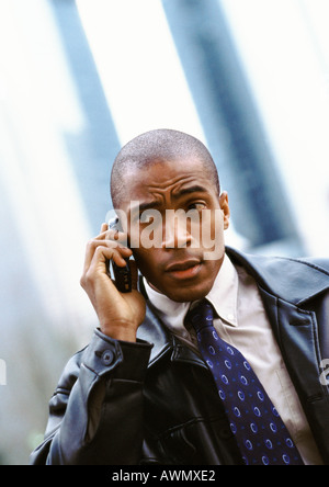 Businessman using cellular phone and furrowing brow, portrait. Stock Photo