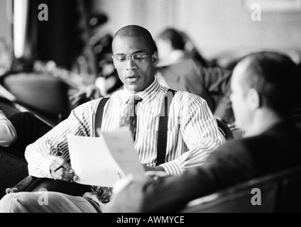 Businessmen sitting together looking over papers, b&w. Stock Photo