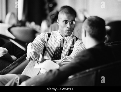 Businessmen sitting, discussing document, b&w. Stock Photo