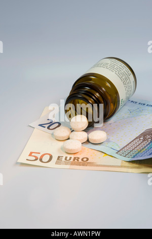 Prescription drugs are getting more expensive: pills tumbling from pill bottle onto Euro notes Stock Photo