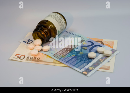 Prescription drugs are getting more expensive: pills tumbling from pill bottle onto Euro notes Stock Photo