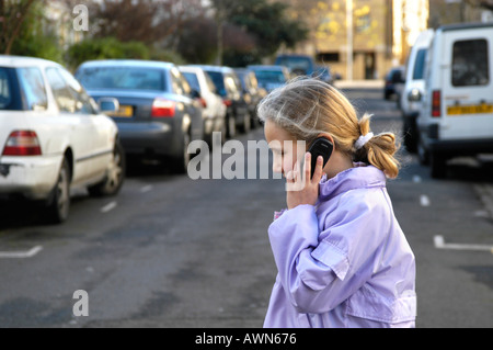 Child talking on mobile phone while crossing the road, London, England UK Stock Photo