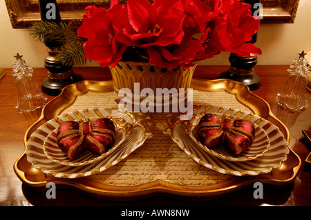 Christmas decorations on a tray with red artificial flowers in vase Stock Photo