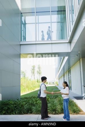 Two students shaking hands on campus Stock Photo