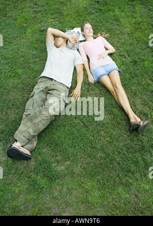 Young couple lying in grass with heads resting on books, high angle view Stock Photo