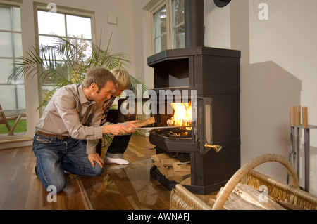 Man and boy firing an oven with wood, low-energy house, Kleinmachnow, Brandenburg, Germany Stock Photo