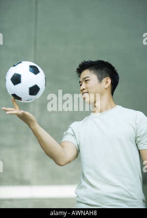 Young man balancing soccer ball on finger Stock Photo