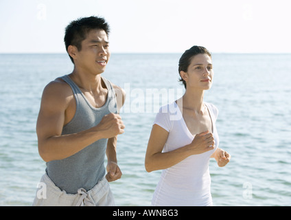 Couple running next to ocean Stock Photo