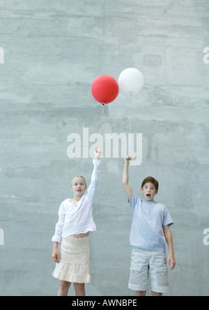 Two children holding balloons, making faces Stock Photo