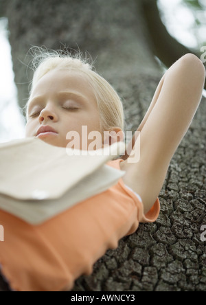 Girl in tree sleeping with book on chest