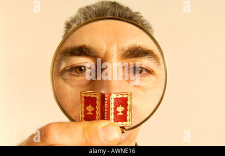 A man taking a close look at tiny ancient book Stock Photo