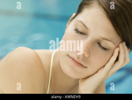 Woman lounging by pool, eyes closed Stock Photo