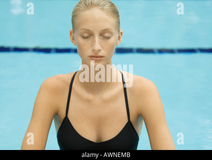 Woman, eyes closed, head and shoulders, pool in background Stock Photo