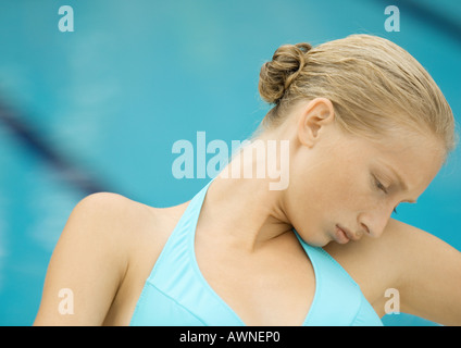 Woman in bikini sitting by pool, head on shoulder Stock Photo