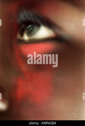 Woman's eye looking up with red make-up on face, close-up, blurred Stock Photo