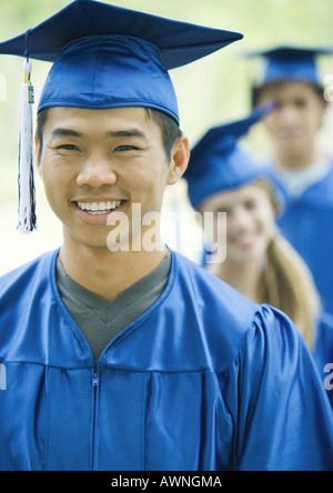 Graduates standing in line, focus on young man in foreground Stock Photo