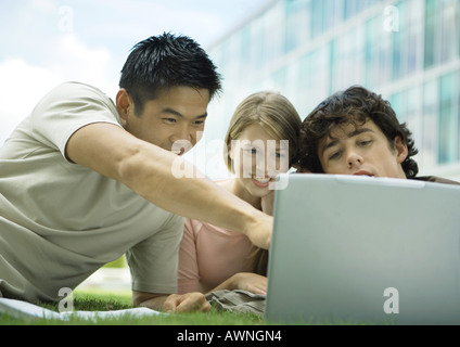 Three college students using laptop outdoors Stock Photo