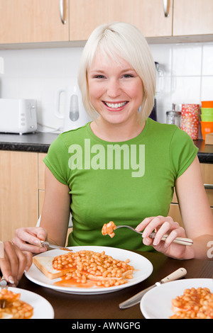 Young woman eating beans on toast