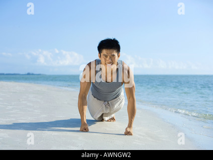 Man doing push-ups on beach Stock Photo